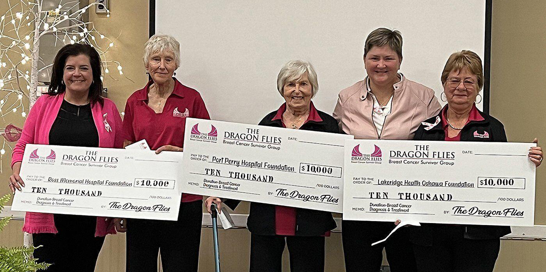 Three women holding giant cheques